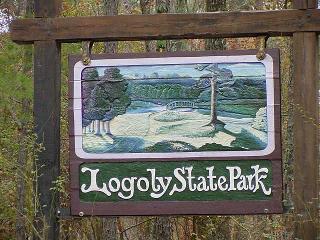 Sign for Logoly State Park featuring a painted landscape with trees and a bridge over a river.