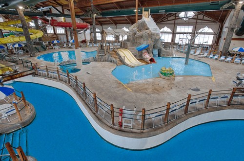 Indoor water park featuring slides, pools, and a lazy river, with a tropical theme and seating areas.
