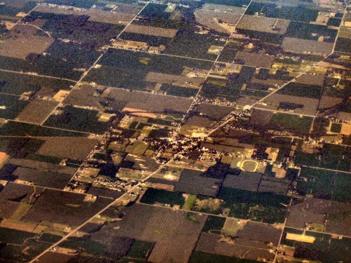Aerial view of a rural landscape with patchwork fields and a small town surrounded by farmland.