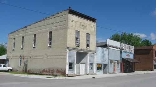 A small town street featuring a mix of brick and wooden buildings under a clear blue sky.