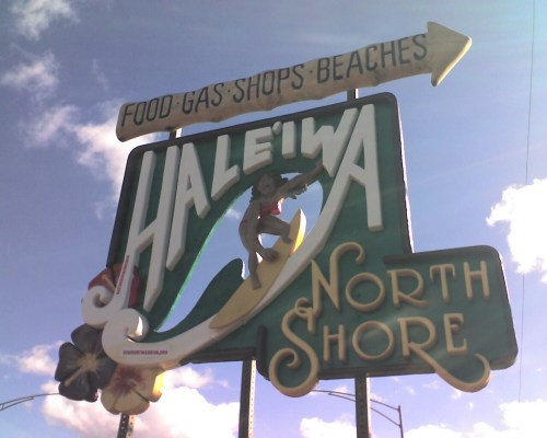Sign for Haleiwa, North Shore, featuring a surfer and indicating food, gas, shops, and beaches.