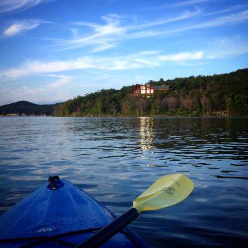 A kayak on calm water, with a scenic shoreline and blue sky in the background.