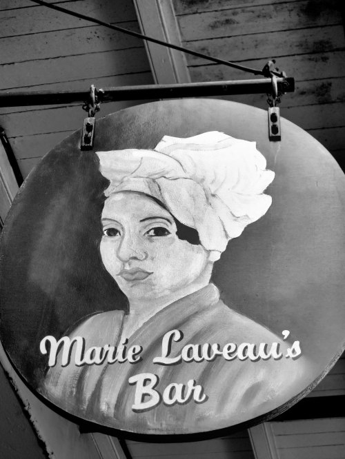 Sign for Marie Laveau's Bar featuring a black-and-white portrait of a woman with a head wrap.