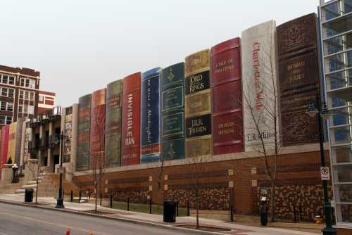 A wall featuring large, colorful book covers, showcasing classic titles in a city setting.