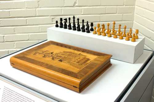 A wooden chess set with black and yellow pieces displayed beside an intricately designed wooden box.