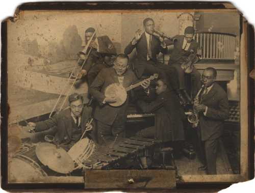 A vintage photo of a jazz band performing, featuring musicians with various instruments in a lively setting.