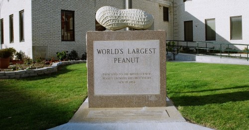 A large stone monument with a peanut sculpture, labeled "World's Largest Peanut," in a grassy area.