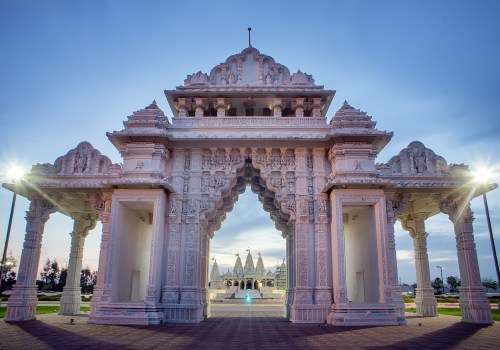 A beautifully carved white temple entrance at dusk, featuring intricate designs and soft lighting.