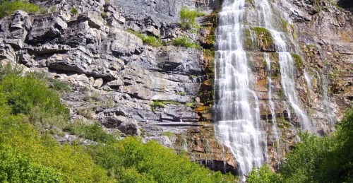A stunning waterfall cascading down rocky cliffs, surrounded by lush green foliage.