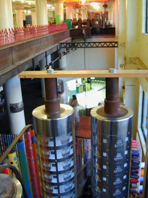 Interior view of a colorful industrial space with large metal cylinders and vibrant decorations in the background.