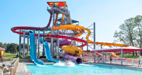 A colorful water slide complex with multiple slides and a pool, under a clear blue sky.