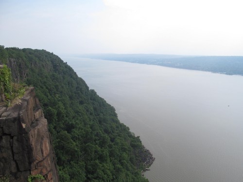 A scenic view of a river winding through lush green hills under a cloudy sky.