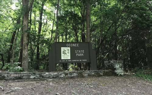 Sign for Oconee State Park surrounded by trees, indicating the entrance to the park.