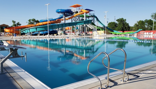 A clear swimming pool with slides in the background on a sunny day.