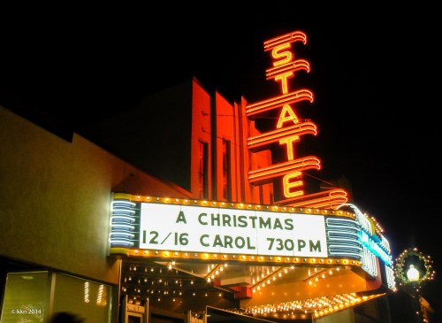 A vintage theater marquee lit up at night, advertising "A Christmas Carol" on December 16 at 7:30 PM.