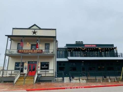 Historic building with a star emblem, featuring a two-story structure and outdoor seating, under a cloudy sky.