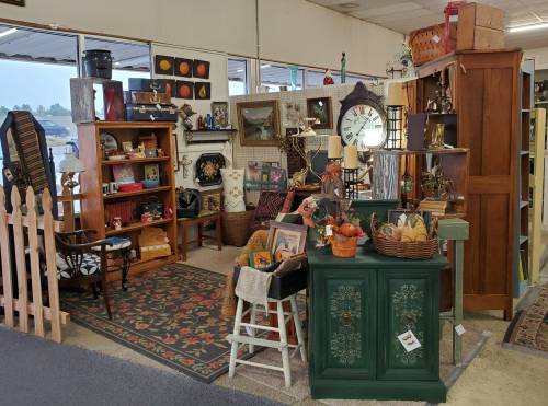 A cozy antique shop corner filled with vintage furniture, decor, and collectibles, featuring a green cabinet and a patterned rug.