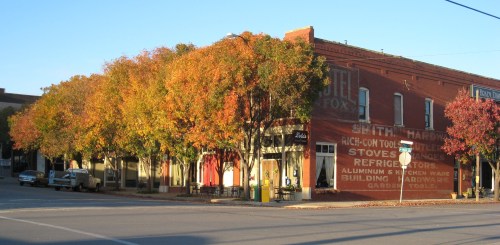 A quaint street corner with colorful autumn trees and historic brick buildings in a small town.