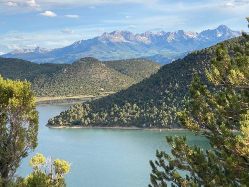 Scenic view of mountains and a lake surrounded by lush greenery under a clear blue sky.
