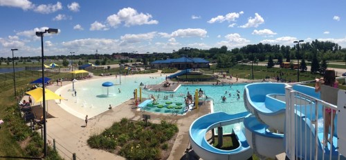 A sunny outdoor water park with slides, a pool, and people enjoying the water on a clear day.