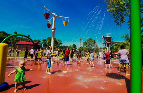 Children play in a vibrant splash pad, enjoying water features and sunny weather on a fun summer day.