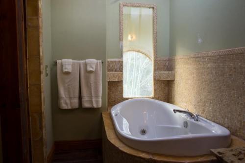 A cozy bathroom featuring a white bathtub, two towels hanging, and a window with soft natural light.