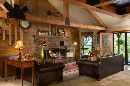 Cozy living room with wooden beams, a brick fireplace, and comfortable seating, featuring warm lighting and a welcoming atmosphere.