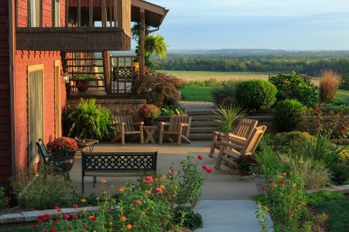A serene outdoor patio with wooden chairs, colorful flowers, and a scenic view of rolling hills in the background.