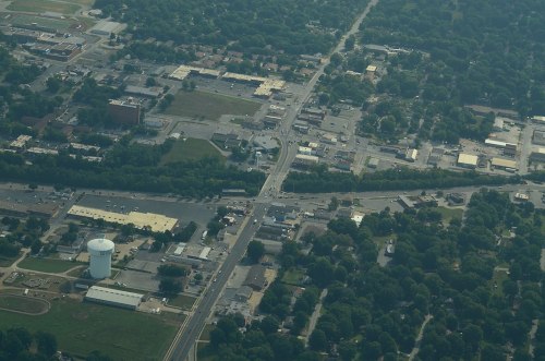 Aerial view of a small town with roads, buildings, and greenery, showcasing a mix of urban and rural landscapes.