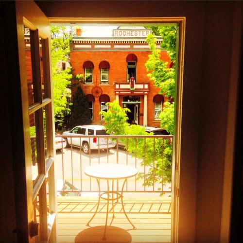 View from an open door onto a balcony, overlooking a street with trees and a building labeled "Rochester."