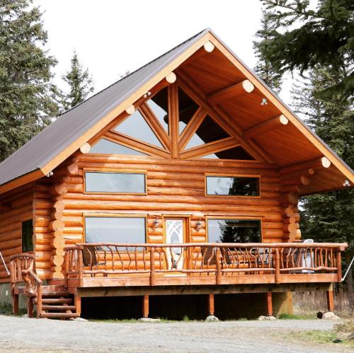 A rustic log cabin with large windows and a peaked roof, surrounded by trees.