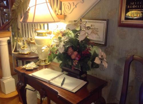 A wooden table with a floral arrangement, a lamp, and an open notebook, set in a cozy, decorated interior.