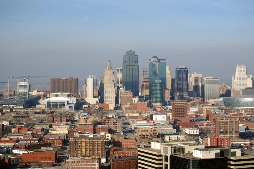 A panoramic view of a city skyline featuring tall buildings and a clear blue sky.