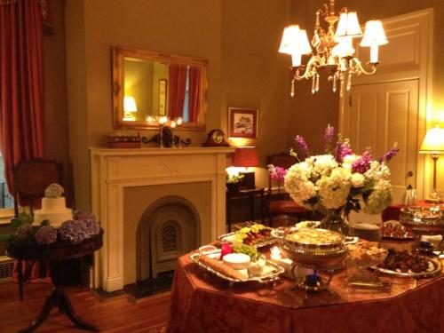 Elegant dining room with a chandelier, a fireplace, and a table set with a variety of dishes and floral arrangements.