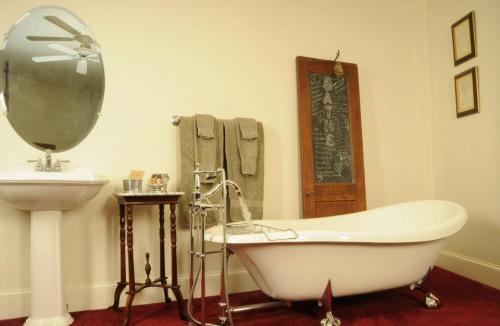 A vintage bathroom featuring a freestanding tub, sink, towels, and a decorative door.
