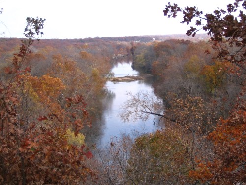 A serene river winding through autumn trees with vibrant orange and yellow foliage.