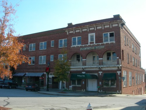 Historic brick building with balconies, labeled "Plantation House," and a nearby shop called "Village Inn."