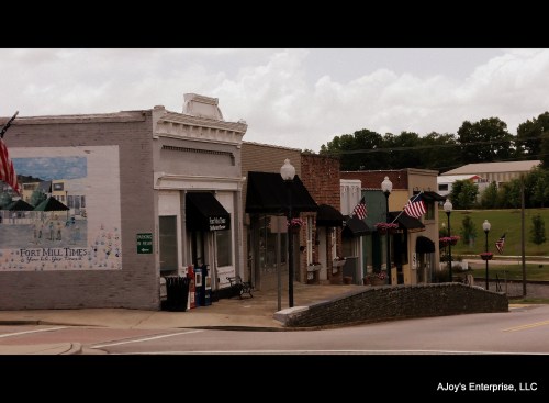 A quaint street scene featuring storefronts with American flags and a mural in a small town.