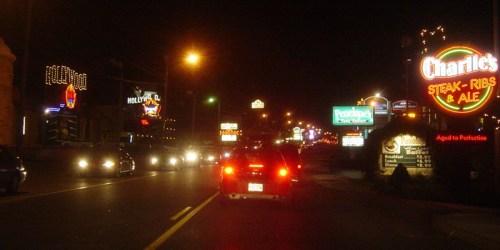 A nighttime street scene with illuminated restaurant signs and traffic, creating a vibrant urban atmosphere.