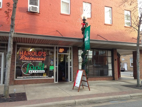 Exterior of Harold's Restaurant, featuring a sign, festive decorations, and a sidewalk menu board.