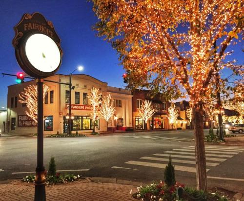 A charming street corner in Fairhope, adorned with festive lights and a clock, at dusk.