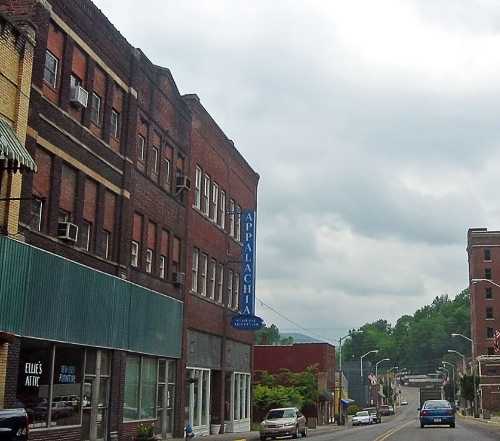 A street view of a small town featuring brick buildings and a sign for "Appalachian" under a cloudy sky.