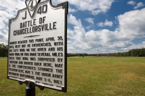 Historical marker for the Battle of Chancellorsville, with a grassy field and cloudy sky in the background.
