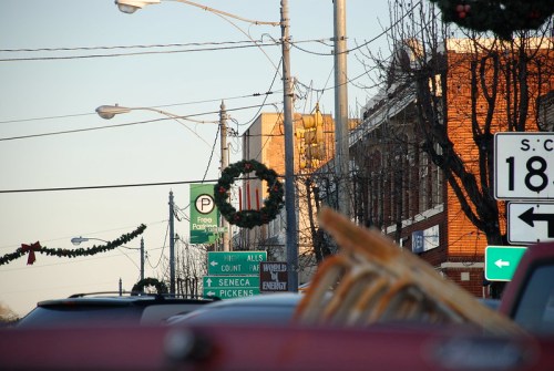 Street view with holiday wreaths, traffic signs, and buildings in the background, capturing a festive atmosphere.