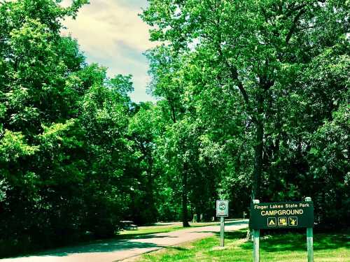 Sign for Finger Lakes State Park Campground surrounded by lush green trees and a clear blue sky.