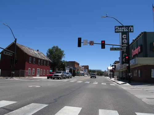 A quiet street scene with traffic lights, a diner sign, and a red building under a clear blue sky.