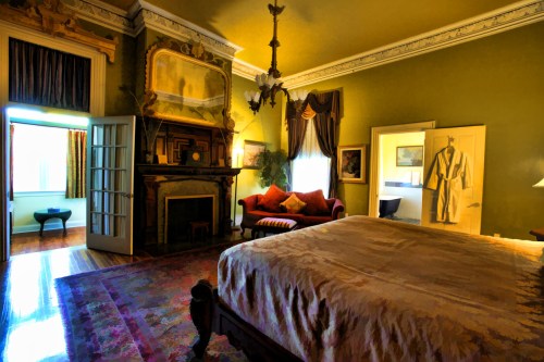 A luxurious bedroom with a large bed, ornate fireplace, elegant decor, and a cozy seating area.