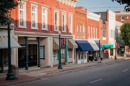 A quiet street lined with charming brick storefronts and awnings in a small town.