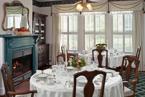 Elegant dining room with round tables set for a meal, a fireplace, and large windows with soft curtains.