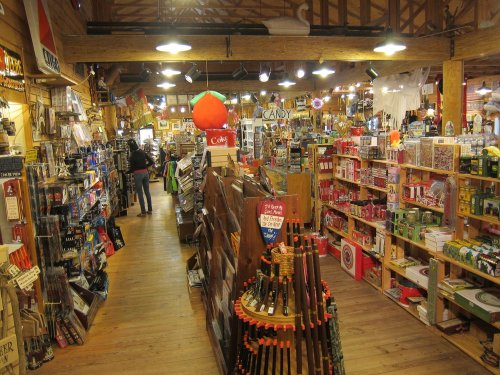 A colorful store interior filled with various merchandise, including toys, candy, and household items, with wooden shelves.